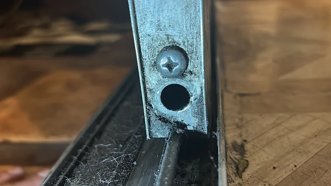 Close-up of a worn sliding door track filled with grime